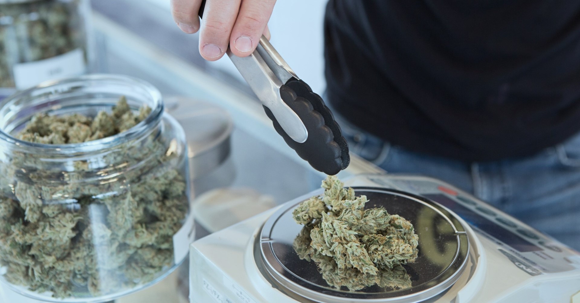 A person holding grey tongs and weighing kush